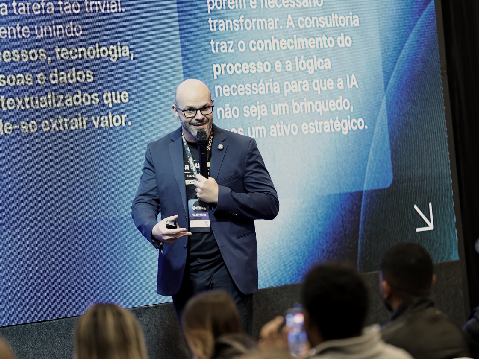 Robson Del Fiol palestrando no StartSe AI Festival com microfone e crachá de palestrante